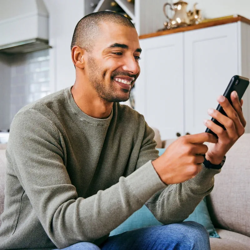 a young man accesses tele-dental services on his smartphone at home